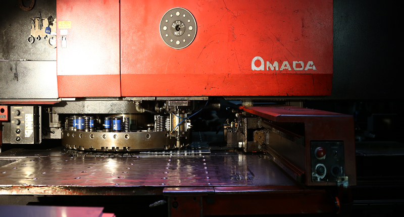 מכונת ניקוב AMADA - בעבודה על פח מתכת מנירוסטה, כחלק מיצור סדרתי. ברצפת היצור של א.ד.ה.פ תעשיות.
